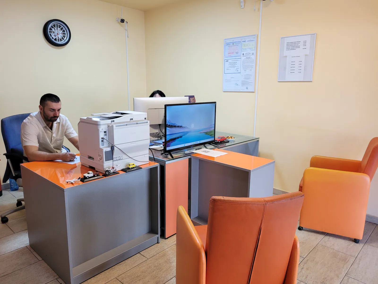Zona de așteptare a biroului, cu fotoliile pentru clienți și certificatele pe perete